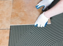 Płytki układa się na równo rozprowadzonej warstwie zaprawy klejącej. układanie płytek, płytki ceramiczne