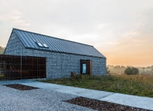 Zimna, północna ściana domu nie ma okien. Jedynie to osadzone w drewnianym wykuszu skierowanym w stronę wschodnią, łapie promienie porannego słońca i daje wgląd na podjazd dom nowoczesny, gabiony, elewacja z gabionów, domy na wsi