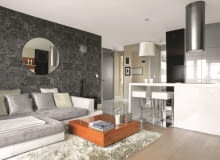 Pan Mariusz pracuje jako stylista mody, każdego dnia otacza go więc mnóstwo kolorów. Nic dziwnego, że w domu chciał odpocząć od nadmiaru barw. Wymarzył sobie mieszkanie spokojne, przytulne, nowoczesne i... monochromatyczne. <BR /> MIESZKANIE. Dominacja szarości i bieli została przełamana pojedynczymi meblami fornirowanymi drewnem orzechowym. Wzór winylowej tapety imituje zwierzęcą sierść. Okrągłe lustro przypominające ogromną płytę CD to prezent od przyjaciół z okazji parapetówki. OLYMPUS DIGITAL CAMERA