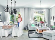 OD RAZU JAŚNIEJ. Ciemny stary kredens od teściów właścicielka przemalowała na biało. Do niego dobrała stół i krzesła z IKEA w tym samym kolorze, a całość przełamała czarnymi lampami ze sklepu Nowodvorski Lighting. Kanapa jest z MTI Furninova, dywan - z IKEA, żyrandol - również z firmy Nowodvorski Lighting. Podłoga to płytki ceramiczne imitujące drewno (marki Imola); gospodyni sama zadecydowała, jak mają być ułożone.