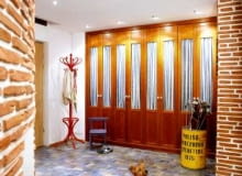 Ceglane ściany w przedpokoju mają nierówną powierzchnię, a dzięki temu - ciekawą fakturę. Jedną ścianę w całości zabudowano nietypowymi przeszklonymi szafami.