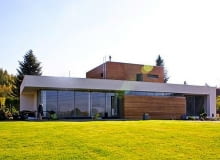 Dom wybudowany według projektu gotowego pracowni Archon+ wygląda trochę jak łódź podwodna wynurzająca się z morza trawy nowoczesny dom