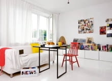 Wszechobecna biel powiększa optycznie małe mieszkanie (38 m kw.). Blaty szafek (takie same wiszą w kuchni) pełnią funkcję biblioteczki i miejsca na bibeloty i zdjęcia. Na podłodze - malowane deski. Kotka Sissy, trzeci domownik, puszy się na oparciu kanapy.