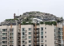 Dwupiętrowa rezydencja na szczycie 26-piętrowego wieżowca. This Aug. 12, 2013 photo released by Chinas Xinhua News Agency shows a residential building with a rocky style villa on its roof, in Haidian District of Beijing, China. Beijing authorities are planning to demolish the bizarre rooftop villa embedded in rocks, trees and bushes that allegedly was built illegally atop a 26-story apartment block in the capital. (AP Photo/Xinhua, Luo Xiaoguang) NO SALES
