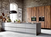 Kuchnia Oktawia+ z linii Prestige+, wykonana z płyty melaminowanej wysokiej jakości: wyspa w ciemnoszarym kolorze Satin Mat, zabudowa w tle z laminatu Palisander Flader. Palisander: kolor drewna egzotycznego w aranżacji wnętrz