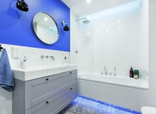 BIEL PŁYTEK I SZAROŚĆ MEBLI ożywia farba w odcieniu indygo, którą pomalowano fragment jednej ze ścian. Łazienkę oświetlają listwy LED zainstalowane pod wanną i nad nią (za załomem podwieszanego sufitu), halogeny zamontowane w suficie oraz kinkiety (Kartell) przy lustrze. BIEL PŁYTEK I SZAROŚĆ MEBLI ożywia farba w odcieniu indygo, którą pomalowano fragment jednej ze ścian. Łazienkę oświetlają listwy LED zainstalowane pod wanną i nad nią (za załomem podwieszanego sufitu), halogeny zamontowane w suficie oraz kinkiety (Kartell) przy lustrze./fot. mat. red.