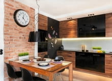 Zamiast jednego centralnego źródła światła - cztery podwójne halogeny (firmy Aquaform), zainstalowane w regularnych odstępach w podwieszonym suficie. Nie tylko rozjaśniają one całą kuchnię, ale także doświetlają blat roboczy. Większość szafek ma fronty fornirowane orzechem amerykańskim (z tego drewna jest również stół), pozostałe są z lakierowanej na czarno płyty MDF. Podłoga, wbrew pozorom, nie jest wyłożona drewnem, ale imitującym je gresem. Płytki o różnej szerokości ułożono 'na mijankę'. Przy cokołach szafek stojących zamontowano wodoodporną taśmę LED. Jej ciepłe światło jest efektowną ozdobą zwłaszcza po zmroku, gdy inne źródła światła w kuchni są wyłączone. Kuchnia, oświetlenie, meble kuchenne