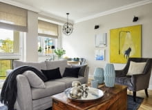 OKNA w pokoju dziennym wychodzą na południowy wschód, dlatego oprócz ozdobnych rolet rzymskich z lnu (Lniany Zaułek) są też rolety nieprzepuszczające światła. Obrazy gospodyni wybrała w galerii internetowej alesztuka.com. Autorem dużego obrazu z psem jest Filip Pręgowski, dwóch mniejszych Agata Kosmala. Poduszki i dywan są ze sklepu twojerolety.pl, kanapa z Furninova, a fotel - z TK Maxx. Niebieskie wazony i tacę z lustrzanymi kulami kupiono w Decoretro.