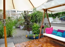 WIDOK TARASU Z KĄCIKA KAWOWEGO. Na pierwszym planie drewniana huśtawka, w głębi podniebna "plaża". WIDOK TARASU Z KĄCIKA KAWOWEGO. Na pierwszym planie drewniana huśtawka, w głębi podniebna "plaża".