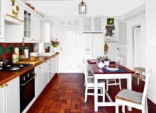 Ustawiony centralnie duży stół zachęca do nieśpiesznego biesiadowania. Klimat tej kuchni stylizowanej na angielską dodatkowo podkreślają ażurowe fronty szafek zabudowujących wnęki w krótszej ścianie.