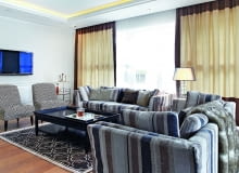 Sofy w oryginalne pasy bronią się dzięki stonowanej kolorystyce. na biało. W oknach zasłony na podszewce, pod nimi rolety rzymskie z półprzejrzystej, białej tkaniny. Sofy Fama, fotele Antoinette, stół kawowy Franco, dywan Casablanca Terra (wszystkie przedmioty BBHome).