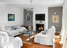 Wokół kominka (i zamontowanego nad nim telewizora) skupia się domowe życie. Zanim kominek został zbudowany, projektantka zrobiła jego tekturową makietę w skali 1:1, żeby sprawdzić, czy proporcje są odpowiednie. Po lewej obraz Stasysa Eidrigeviciusa, po prawej baletnica Bereniki Koreckiej; nad kanapą płótno Alicji Słaboń-Urbaniak. Drewniany świecznik stojący na podłodze to nabytek z paryskiego targu staroci, latarenka na stoliku - ze sklepu BBHome. Salon z kominkiem, kominek, wystrój salonu