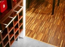 Między parkietem a płytkami ceramicznymi ułożono tzw. listwę dylatacyjną. Zakrywa ona szczelinę - niezbędną w tym miejscu, by drewno mogło 'pracować'. Projekt wnętrza: Radosław Guzowski