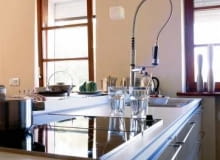 Zabudowa tworząca kuchenną wyspę jest zrobiona z takiego samego drewna jak meble w salonie. Dzięki temu wnętrza stanowią jednolitą stylistycznie całość.