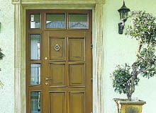 Jasna kolorystyka elewacji to również jasne drzwi. Ich urodę podkreśla ozdobne obramowanie drzwi i przeszklona ścianka.