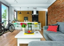 WNETRZE JEST PRZYTULNE mimo użycia surowych materiałów - cegły i betonu. Dużo ciepła wprowadziło drewno i akcenty żywych kolorów: przemalowane krzesła przy wyspie (modele Idolf z IKEA) oraz poduszki z Modalto i IKEA (na kanapie kupionej w Modalto).