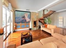 Gospodarze kochają podróże, co znalazło odzwierciedlenie w wystroju domu. Do ich wojaży po bliższych i dalszych zakątkach świata nawiązują nie tylko rozstawione po całym wnętrzu pamiątki, ale także egzotyczne gatunki drewna i... kolorystyka błękitnej jak ocean sypialni. <BR /> DOM. Ściana ciekawie zaaranżowana. Okno przesłonięte ekranem, na którym gospodarze oglądają filmy z projektora, to w rzeczywistości wbudowany w ścianę regał. Dwanaście frontów z  mlecznego szkła ujęto w ramę z palisandru. Tym samym materiałem obramowano palenisko kominka wyłożonego płytami wielobarwnego łupka. Na podłodze - orzech amerykański. Gospodarze kochają podróże, co znalazło odzwierciedlenie w wystroju domu. Do ich wojaży po bliższych i dalszych zakątkach świata nawiązują nie tylko rozstawione po całym wnętrzu pamiątki, ale także egzotyczne gatunki drewna i... kolorystyka błękitnej jak ocean sypialni. <BR /> DOM. Ściana ciekawie zaaranżowana. Okno przesłonięte ekranem, na którym gospodarze oglądają filmy z projektora, to w rzeczywistości wbudowany w ścianę regał. Dwanaście frontów z  mlecznego szkła ujęto w ramę z palisandru. Tym samym materiałem obramowano palenisko kominka wyłożonego płytami wielobarwnego łupka. Na podłodze - orzech amerykański.