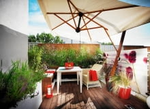 <B>Wystarczyły dwa tygodnie, by taras z betonu i stali na dachu budynku w środku miasta zmienił się w cichy, idylliczny zakątek, w którym gospodarze czują się jak na wiejskiej łące. Skąd takie wrażenie? Wywołują je użyte materiały, zwłaszcza naturalne drewno, oraz doniczkowe rabatki skomponowane z kwitnących wśród traw delikatnych roślin.</B> <BR /> METAMORFOZA TARASU. Płotek zasłania widoczną z tarasu konstrukcję dachu i zapewnia bezpieczeństwo. Zrobiono go z thermojesionu (dzięki obróbce w wysokiej temperaturze drewno ciemnieje i nabiera odporności). <BR /> Meble ze sztucznego rattanu są odporne na deszcz i śnieg, dzięki czemu nie trzeba ich przenosić na zimę do mieszkania. Rozłożony w upalne dni parasol daje upragniony cień. <BR /> Na ekranie z pleksi nadrukowano bordowe kwiaty zawciągu nadmorskiego. Ekran nie tylko zdobi taras, ale również chroni domowników przed wzrokiem sąsiadów i zasłania widok na miasto. taras, metamorfoza, aranżacja tarasu, balkon, meble na balkon