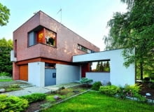 Widok na elewację frontową od strony ulicy. Układ brył budynku jest konsekwencją ukształtowania terenu działki elewacja frontowa, nowoczesny dom