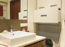 Pralkę przesłaniają drzwi z aluminiowych żaluzji. Nad nią we wnęce znajdują się szuflady i szafka z płyty MDF zamykana drzwiczkami. Pralkę przesłaniają drzwi z aluminiowych żaluzji. Nad nią we wnęce znajdują się szuflady i szafka z płyty MDF zamykana drzwiczkami.