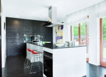 W tym domu rodzina i znajomi najchętniej zbierają się wokół dwóch mebli - stołu w jadalni oraz wyspy, zajmującej w kuchni centralne miejsce. Jest ona na tyle duża (323 x 123 cm), że może przy niej wspólnie gotować kilka osób, nie przeszkadzając sobie nawzajem; mniej zaangażowani w pracę będą w tym czasie"kibicować", siedząc na stołkach barowych. Całą kuchnię zaaranżowano w czerni i bieli; blat wyspy i podłoga są z granitu, fronty wysokiej zabudowy - z płyty MDF fornirowanej szczotkowanym i bejcowanym dębem. W tym domu rodzina i znajomi najchętniej zbierają się wokół dwóch mebli - stołu w jadalni oraz wyspy, zajmującej w kuchni centralne miejsce. Jest ona na tyle duża (323 x 123 cm), że może przy niej wspólnie gotować kilka osób, nie przeszkadzając sobie nawzajem; mniej zaangażowani w pracę będą w tym czasie"kibicować", siedząc na stołkach barowych. Całą kuchnię zaaranżowano w czerni i bieli; blat wyspy i podłoga są z granitu, fronty wysokiej zabudowy - z płyty MDF fornirowanej szczotkowanym i bejcowanym dębem.