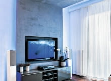 <B> Dawniej potrzebowały solidnej szafki, dziś lekkie i płaskie telewizory coraz częściej wieszamy na ścianie. Projektanci wnętrz proponują różne rozwiązania, dzięki którym miejsce do oglądania wygląda ładnie i jest wygodne. </B><BR /> TELEWIZORY: Projektant chciał, aby salon wyróżniał się z reszty mieszkania. Motywem przewodnim aranżacji stał się kształt litery C. Tworzą ją płyty gipsowo-kartonowe pokryte dekoracyjnym tynkiem imitującym beton, które zamontowano pod sufitem i na części ściany, oraz docięta na wymiar wykładzina dywanowa (podstawa C). Formę tej litery ma również stolik kawowy przy kanapie. <B> Dawniej potrzebowały solidnej szafki, dziś lekkie i płaskie telewizory coraz częściej wieszamy na ścianie. Projektanci wnętrz proponują różne rozwiązania, dzięki którym miejsce do oglądania wygląda ładnie i jest wygodne. </B><BR /> TELEWIZORY: Projektant chciał, aby salon wyróżniał się z reszty mieszkania. Motywem przewodnim aranżacji stał się kształt litery C. Tworzą ją płyty gipsowo-kartonowe pokryte dekoracyjnym tynkiem imitującym beton, które zamontowano pod sufitem i na części ściany, oraz docięta na wymiar wykładzina dywanowa (podstawa C). Formę tej litery ma również stolik kawowy przy kanapie.