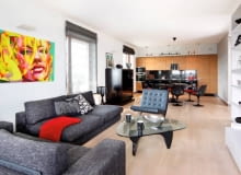 W kuchni zainstalowano listwy oświetleniowe z halogenami, nad stołem jest lampa wisząca, a w części wypoczynkowej - kinkiety i reflektorki. We wnętrzu dominują ciemne szarości i czerń rozjaśnione dużymi płaszczyznami bieli i kremowego beżu.