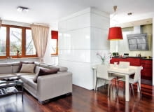 KUCHNIA. Za białymi frontami od strony pokoju kryją się schowki, m.in. barek. Dolne szafki kuchenne z lakierowanej na czerwono płyty MDF są przykryte blatem z konglomeratu kwarcowego - bardzo twardego, odpornego na ścieranie i działanie wysokiej temperatury. KUCHNIA. Za białymi frontami od strony pokoju kryją się schowki, m.in. barek. Dolne szafki kuchenne z lakierowanej na czerwono płyty MDF są przykryte blatem z konglomeratu kwarcowego - bardzo twardego, odpornego na ścieranie i działanie wysokiej temperatury.