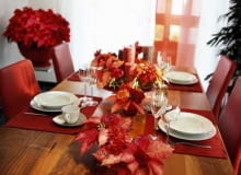 Nastrojowa dekoracja stołu. Poinsecje ułożono w niskich naczyniach z pojedynczymi goździkami i nerine. Nastrojowa dekoracja stołu. Poinsecje ułożono w niskich naczyniach z pojedynczymi goździkami i nerine.