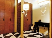 1. Minipałacyk. Architektka, zainspirowana wzorami podłóg często spotykanych w pałacach, zaprojektowała "wariację na temat" z połówek gresowych płytek w czekoladowym i kremowym odcieniu. Do kompletu zaproponowała równie stylową szafę wnękową fornirowaną palisandrem, z zabawnymi chwościkami przy uchwytach. Gospodyni uzupełniła wystrój meblami w stylu kolonialnym - dobrała m.in. stolik kojarzący się z pałacową konsolką - oraz lampami... unoszącymi się w powietrzu. Iluzja jest w każdym razie doskonała. W rzeczywistości kinkiety z płaską nóżką przymocowano do lustra zajmującego niemal całą ścianę.