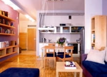 Aneks kuchenny jest integralną częścią salonu. Jasne, gładkie fronty szafek i przeszklone witrynki dają wrażenie lekkości, nie przytłaczają więc wnętrza.