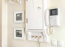 Dzięki naszemu pomysłowi przedpokój z zainstalowanymi na ścianie licznikami lub bezpiecznikami będzie wyglądał bardzo stylowo. Pokazana szafka jest łatwa do zrobienia i - co ważne - niedroga. <BR />Skrzynkę z licznikami lub bezpiecznikami najprościej jest ukryć w szafie ubraniowej - będą tam niewidoczne, a zarazem dostępne w razie potrzeby. Często jednak umiejscowienie tych niezbędnych, lecz nieatrakcyjnych urządzeń jest tak niefortunne, że nie ma mowy o jakiejkolwiek funkcjonalnej skrytce. Tak było w tym przypadku, stąd decyzja o zrobieniu ozdobnej miniszafeczki zharmonizowanej z wystrojem całego przedpokoju. Świetnym rozwiązaniem było umieszczenie obok szafki małych czarno-białych fotografii oprawionych w białe ramki - stanowią przeciwwagę wiszącego po prawej stronie domofonu.