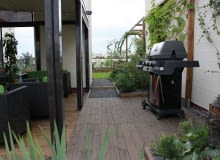 Zielony taras, projekty balkonów. Zadaszona część tarasu z meblami, po prawej stronie, imponujący grill gazowy. taras, balon, ogrody na dachu