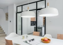 Widok z jadalni w stronę kuchni. Na zdjęciu widać, w jaki sposób skrzydła drzwi „odkładają" się na boki, pod kątem 180 stopni. Takie otwarcie pozwala na wygodną, bezkolizyjną komunikację pomiędzy stołem a kuchnią. Jadalnia w nowoczesnym apartamencie