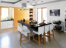 W dużej otwartej kuchni(ok. 30 m kw.) można było sobie pozwolić na umieszczenie wyspy na środku pomieszczenia. Ten spory mebel, 140 x 240 cm, przykryto grubym granitowym blatem, w jego rogu zamontowana została płyta grzejna, a po drugiej stronie stanęły wysokie stołki barowe. Przy ścianie z oknem zaaranżowano ciąg roboczy ze zlewozmywakiem oraz dużą szafę zamykaną przesuwanym panelem; ścianę naprzeciwko drzwi tarasowych zajęła wysoka zabudowa (lepiej widoczna na zdjęciu na następnej stronie). wyspa kuchenna, meble kuchenne, kuchnia