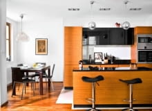 Aranżacje. Nieduży aneks jadalny urządzono we wnęce przy otwartej kuchni. Jego umowną granicę wyznacza podłoga z drewna, taka jak w salonie.<BR />Wygospodarowanie kącika jadalnego w 25-metrowym pomieszczeniu było możliwe dzięki zabudowie kuchennej zajmującej mniej więcej dwie trzecie długości ściany. W niewielkim aneksie z oknem zmieścił się jedynie stół; największą ozdobą jest tam lampa wisząca z oryginalnym kloszem z opalizującego szkła. Funkcję pomocnika, na który stawia się potrawy i odstawia naczynia, pełni wyspa. Przy niej, siedząc na barowych stołkach, można również zjeść niewielki posiłek albo towarzyszyć gospodyni przygotowującej potrawy. Fronty kuchennych szafek są z teku i barwionego szkła, blaty - z granitu. Ścianę nad blatem roboczym chroni tafla szkła. Podłogę w części kuchennej wyłożono gresem; w jadalni i salonie jest egzotyczne drewno panga panga. WNETRZA , KUCHNIA - ANEKS JADALNY , MEBLE