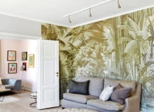 W salonie odpoczywa się pod... palmami, ręcznie odtworzonymi na ściennych panelach w kolorze sepii przez rzemieślników marki de Gournay. Puf pełni także rolę stolika kawowego.