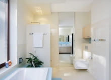 <B>Z wyborem kabiny, w której zamiast tradycyjnego brodzika jest odpowiednio wyprofilowana podłoga, wiąże się wiele korzyści: większa swoboda w decydowaniu o jej kształcie i brak progu w wejściu; poza tym łazienka wydaje się przestronniejsza. Aby takie rozwiązanie sprawdziło się w praktyce, ważne jest skuteczne odprowadzenie wody.</B> <BR >ŁAZIENKA: Z KABINĄ NA MIARĘ. Chociaż na rynku są dostępne kabiny prysznicowe o różnych kształtach i wielkościach, w nowo projektowanych łazienkach coraz częściej pojawiają się kabiny murowane. Za takim wyborem przemawia łatwość wygospodarowania miejsca na natrysk i większe możliwości indywidualnej aranżacji wnętrza. <BR >Ściankę kabiny wyłożono białą mozaiką; z niej zrobiono także obramowanie wysokiego lustra (taflę przyklejono bezpośrednio do ściany) i cokół przy podłodze. We wnęce nad podwieszanym sedesem zawieszono praktyczną szafkę z płyty fornirowanej bielonym dębem.