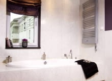 Ściany przy wannie zostały aż po sufit wyłożone jasnymi płytkami ceramicznymi. Pomalowany na ciemnofioletowy kolor sufit przywodzi na myśl rozgwieżdżone niebo. Takie skojarzenia nasuwają się zwłaszcza wieczorem, po włączeniu halogenowych lampek. WNETRZA LAZIENKA OSWIETLENIE HALOGENOWE LAMPKI