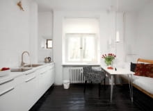 Kuchnia w wariancie 1. Na podłodze - pomalowane na czarno deski, na ścianie przy kuchennych szafkach - cegły pokryte białą farbą. Właścicielce zależało, by zachować jak najwięcej oryginalnych elementów wnętrza. Zmieniła więc tylko nieco ich wygląd.