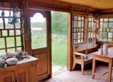 <B>Drewniany dom nad Czarną Hańczą stoi w miejscu, gdzie w epoce kamiennej była osada łowców reniferów, a potem - Jaćwingów. Prawie dwadzieścia lat temu w tej typowej chacie podlaskiej - niemal stuletniej, starannie odbudowanej po pożarze - zamieszkał nasz gospodarz. Trzeba przyznać: siedlisko w sam raz dla artysty. </B> <BR />Widok z ganku. Krąg z kamieni polnych (wśród nich znajduje się też wielki kamień młyński) został ułożony na pamiątkę Jaćwingów - ludu bałtyckiego zamieszkującego niegdyś Podlasie.