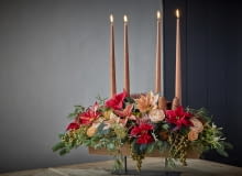 Unoszący się nad stołem, elegancki wieniec wykonany z ciętych poinsecji, suszonych kwiatów - w tym banksji i protei - gałązek palmy daktylowej (Phoenix dactylifera), zielonych gałązek i szyszek ozdobi każde wnętrze. Magia adwentu z poinsecją