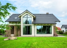 Tradycyjna forma o współczesnym wyglądzie sprawia, że dom łatwo jest wpasować nie tylko w zadbaną okolicę z elegancką stonowaną architekturą. Tego rodzaju zabudowa - nieepatująca ani nadmierną nowoczesnością, ani drastyczną stylizacją - może doskonale uspokoić i uporządkować również bardzo zabałaganione otoczenie ogród