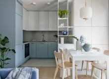 Otwarta, biało-niebieska kuchnia spójnie łączy się poprzez kolory i proste formy z aranżacją części dziennej. Piaskowy gres Marazzi na podłodze nawiązuje barwą do drewnianych akcentów w projekcie.