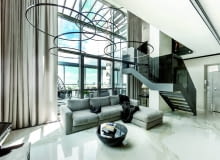 Salon - jasne, przestronne wnętrze, a w nim ciemne akcenty, takie jak czarne schody. Ogromne okna z pięknym widokiem na niebo. Specjalnie zaprojektowane lampy - pierścienie są bardzo delikatne, by nie przysłaniać żadnego jego fragmentu.