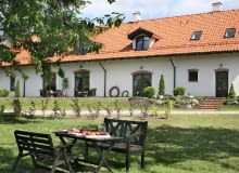 Duże przeszklone drzwi tarasowe w ciemnych ramach kontrastują z bielą ścian i doświetlają wnętrza; z zewnątrz wyglądają jak stare wrota budynku gospodarskiego dom na Mazurach