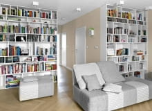 Dwa duże regały, zrobione na wymiar z malowanej płyty MDF, mieszczą domową biblioteczkę. Dwukolorowe, biało-szare meble wypoczynkowe (z firmy Agata) zdradzają zamiłowanie gospodarzy do spokojnych barw. salon, aranżacja salonu