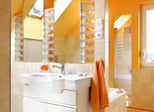 <b> Styl nowoczesny to określenie bardzo pojemne. Wystarczy spojrzeć na prezentowane przez nas trzy łazienki. Wszystkie - mimo że tak różne - hołdują nowym trendom. </b> <BR /> ORANŻOWY ŻAR. Łazienka jest duża, ale jej powierzchnia użytkowa została mocno okrojona przez skosy. Mimo to projektantce bez trudu udało się podzielić wnętrze na wyraźne strefy - przy wannie ustawiono ściankę, a po jej drugiej stronie zainstalowano umywalki. Glazura położona na części ścian i na podłodze ma neutralny odcień. O wyrazistości wnętrza zadecydował odważny pomarańczowy odcień farby, którą pokryto skosy oraz sufit. Lustra zostały obramowane luks- ferami. Zdaniem projektantki to idealny materiał konstrukcyjny, który jednocześnie nie zabiera światła ani przestrzeni. Przy wannie znajduje się zsyp na brudną bieliznę, prowadzący bezpośrednio do pralni na parterze.