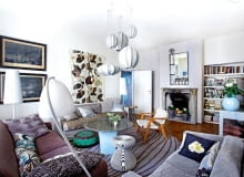 W salonie motywy etniczne przeplatają się z klasycznymi i współczesnymi. Poduchy ubrane w marokańskie hafty, egzotyczny puff, nad oprawą kominka z XVIII wieku zabytkowe lustro. Nad kanapą dwa XIX-wieczne sztychy. przedwojenne mieszkanie, mieszkanie w Warszawie, przedwojenne mieszkanie