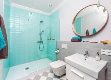 Błękitne płytki typu metro wyznaczają prysznic. W pozostałej części łazienki położono szare płytki. płytki ceramiczne, kolorowe płytki do łazienki